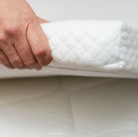 Person holding a white mattress topper on a bed