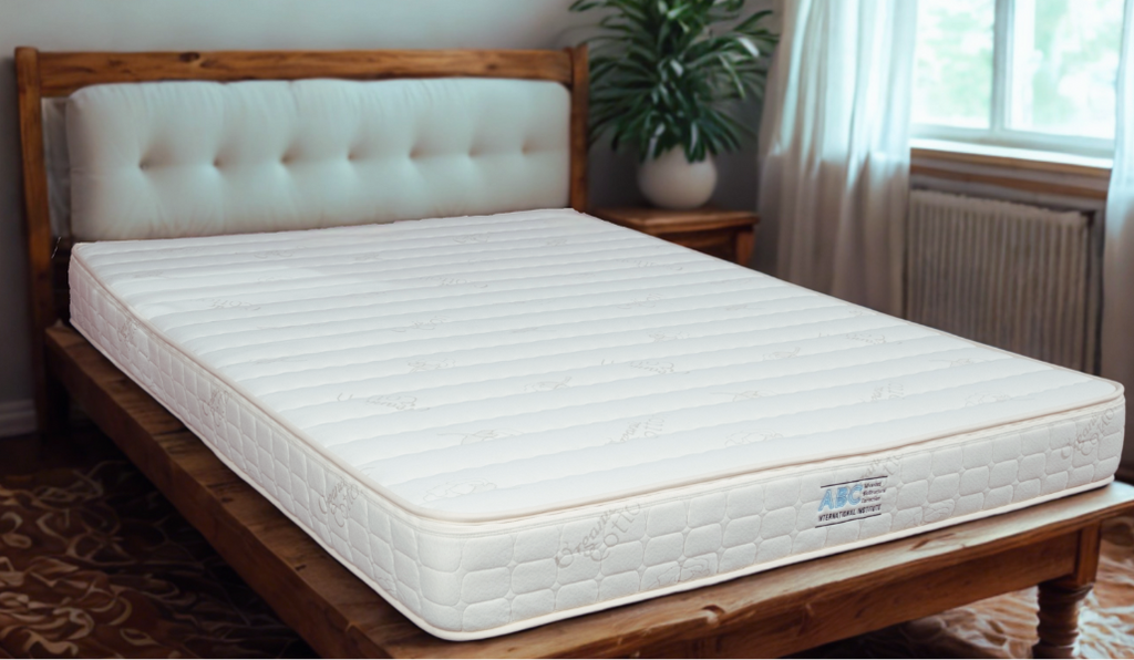 Mattress on a wooden bed frame with a plant and window in the background